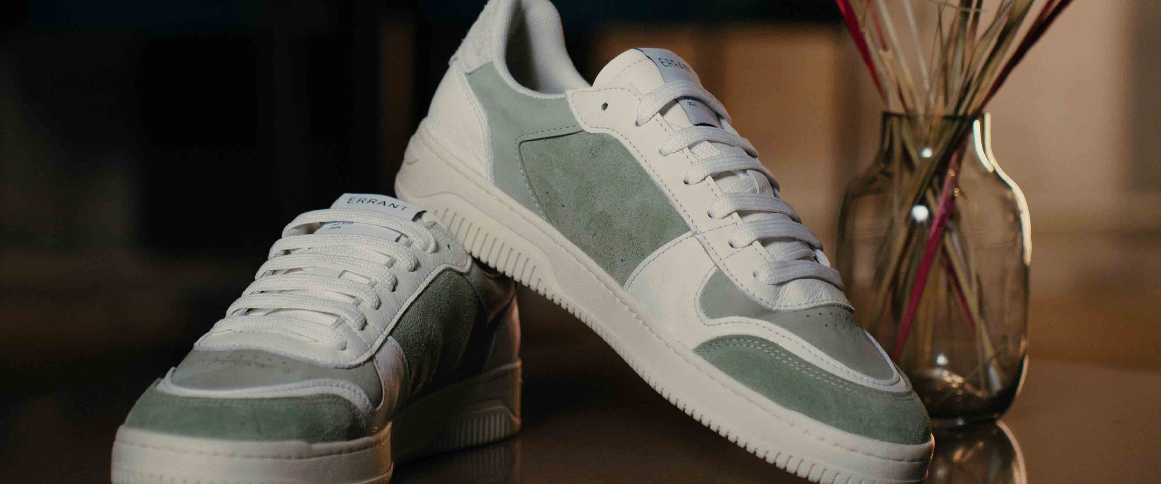 Et par Low Sneaker - Sage Green står på et bord